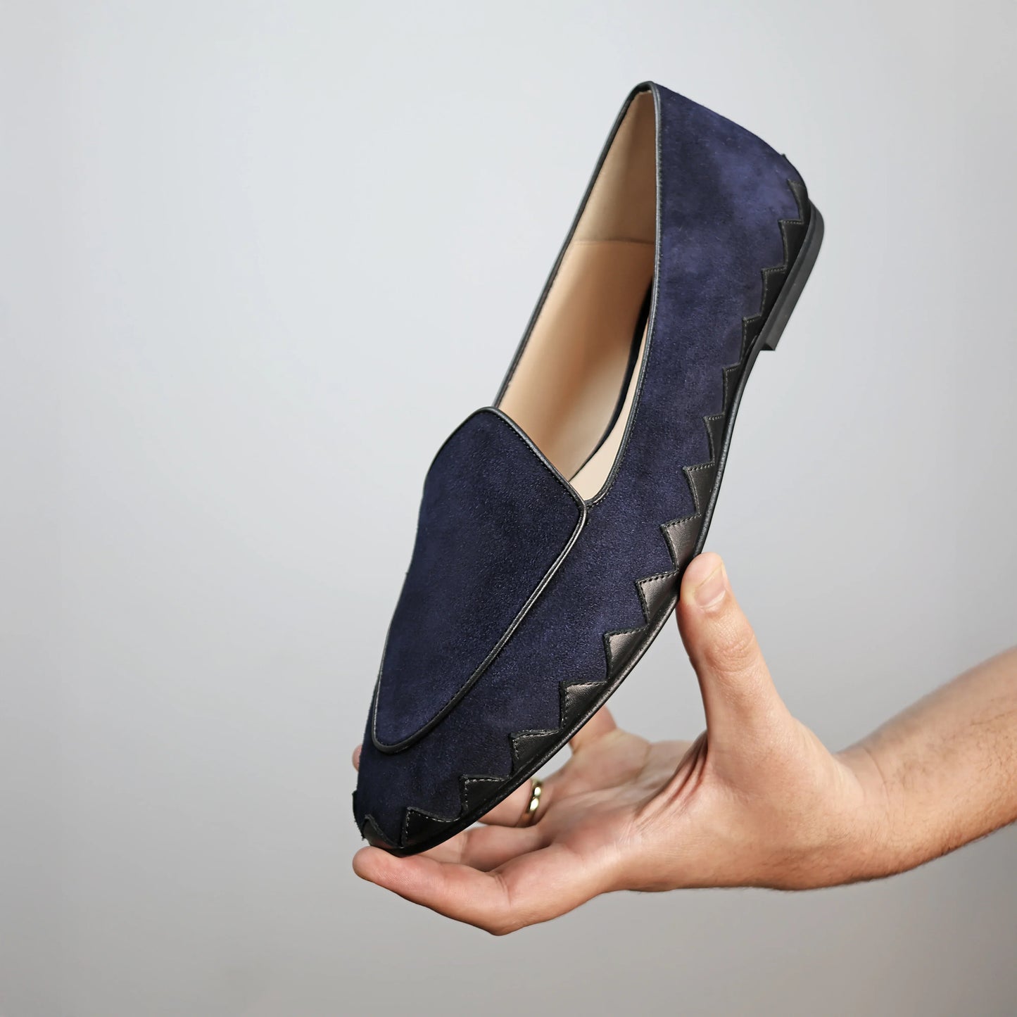 Model holding JB Ander men's Great White smoking slipper loafers in Marino navy suede with unique leather trim, and handmade Italian craftsmanship.