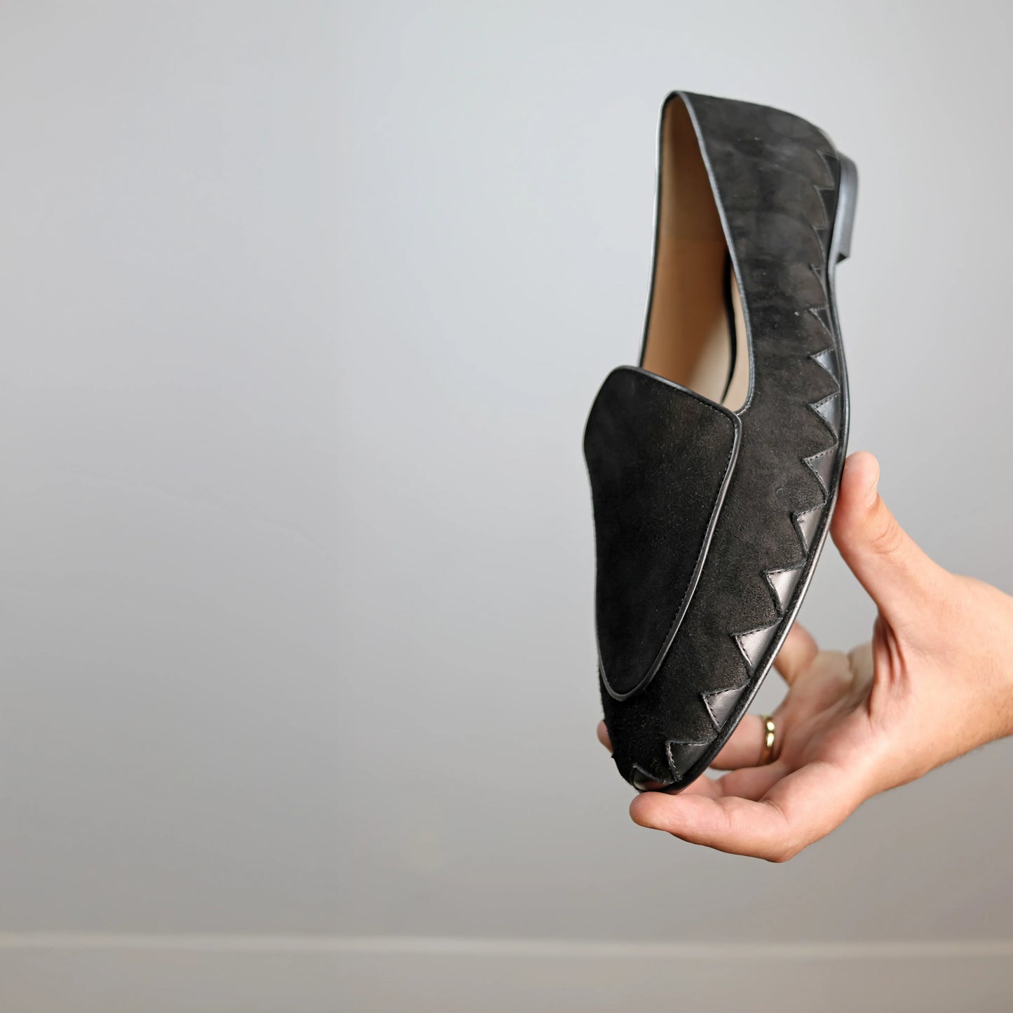 Model holding JB Ander men's Great White smoking slipper loafers in Nero black suede with unique leather trim, and handmade Italian craftsmanship.