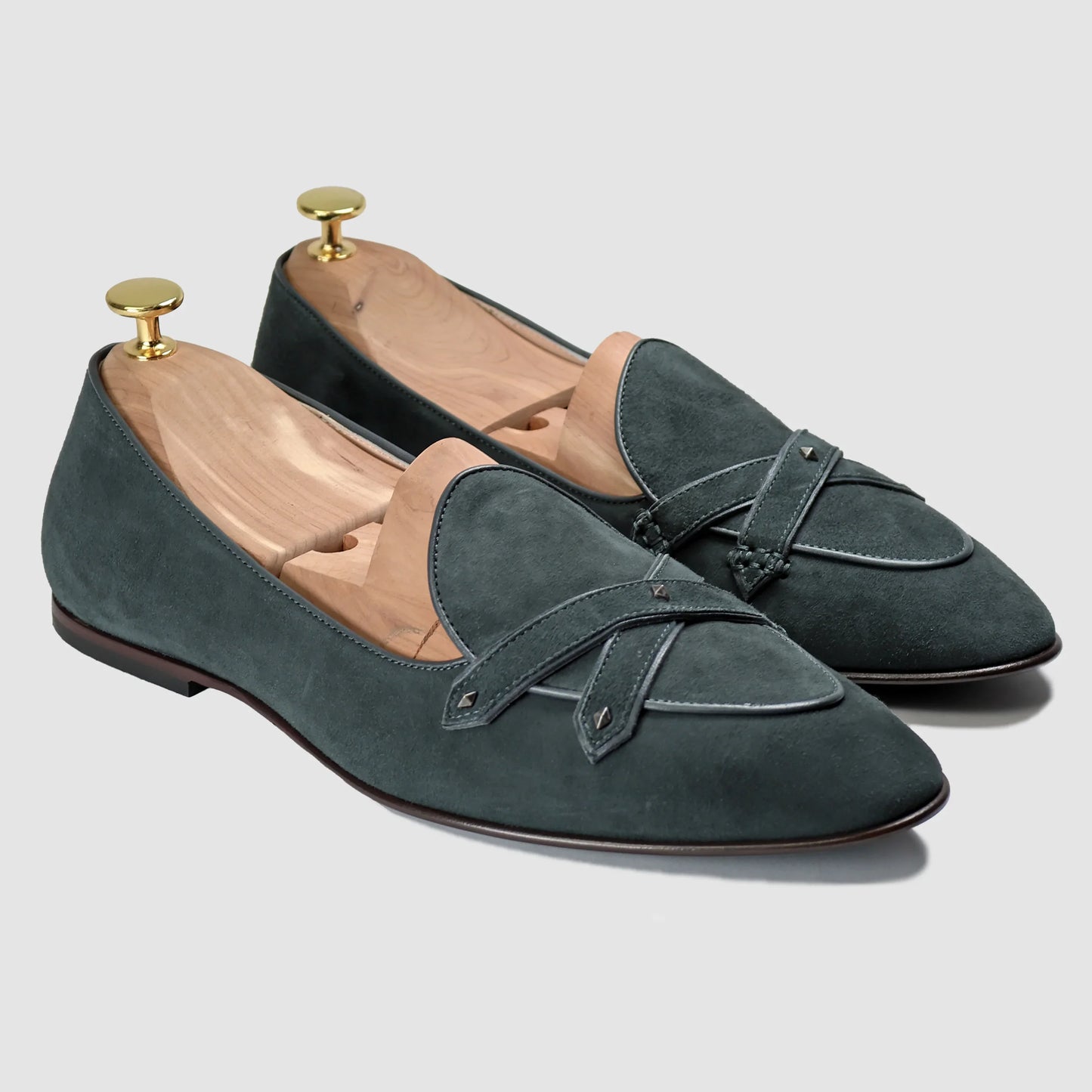 Emerald-green suede Lincoln saddle loafers by JB Ander, front three-quarter angle showing double cross-strap detail, wooden cedar shoe trees, and Italian leather outsole edge.