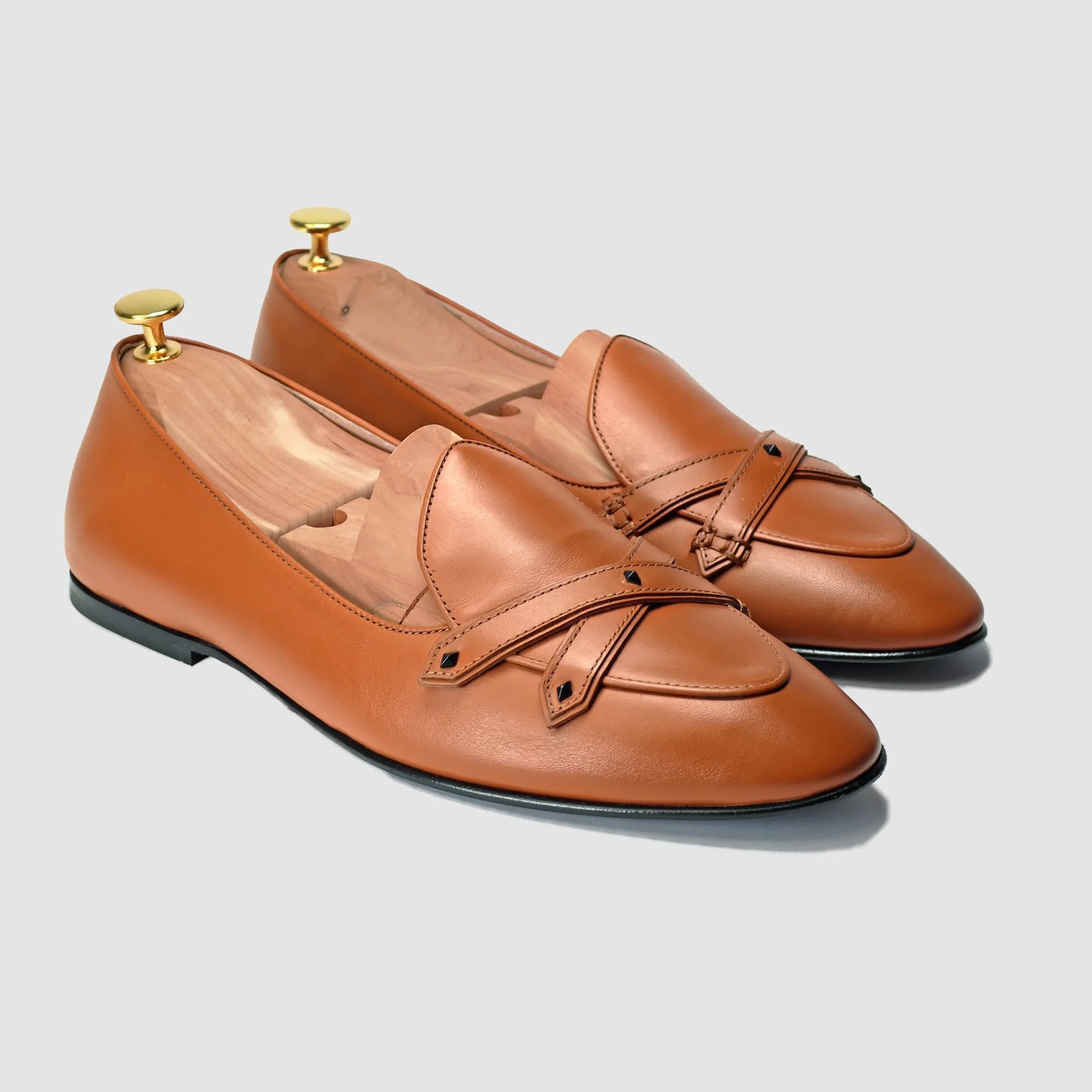 Terracotta leather Lincoln saddle loafers by JB Ander, front three-quarter angle showing double cross-strap detail, wooden cedar shoe trees, and Italian leather outsole edge.