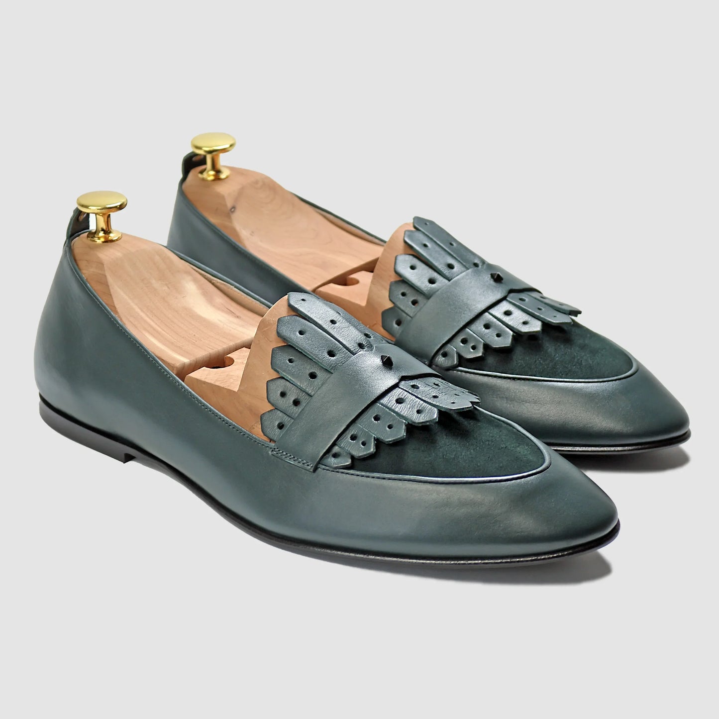 Verde green Italian leather Scottie kilt loafers by JB Ander, front three-quarter angle showing double leather fringe kiltie detail, luxury suede trim, and leather outsole edge.