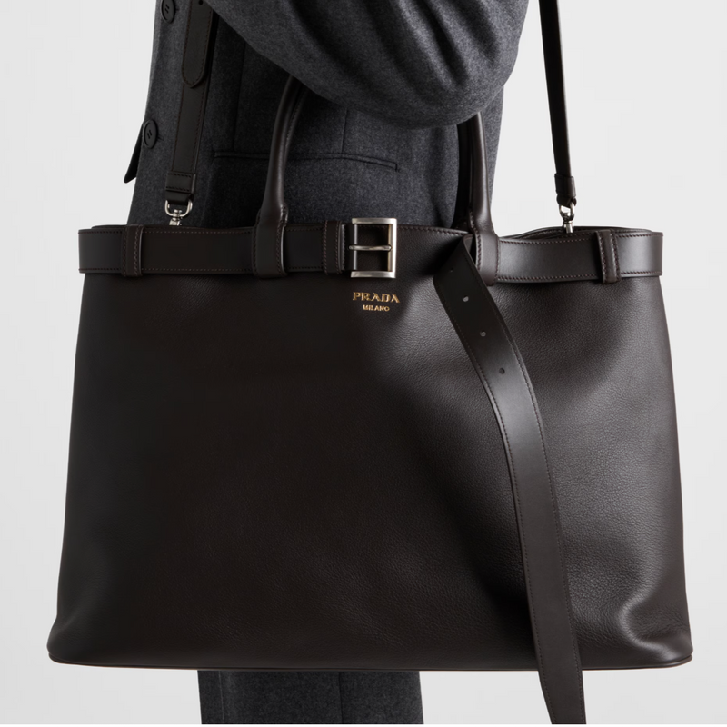 Brown Prada tote bag held by a person on a light gray background
