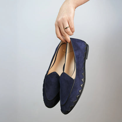Model holding JB Ander men's Great White smoking slipper loafers in Marino navy suede with unique leather trim, and handmade Italian craftsmanship.