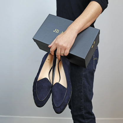 Model holding JB Ander men's Great White smoking slipper loafers in Marino navy suede with unique leather trim, and handmade Italian craftsmanship.