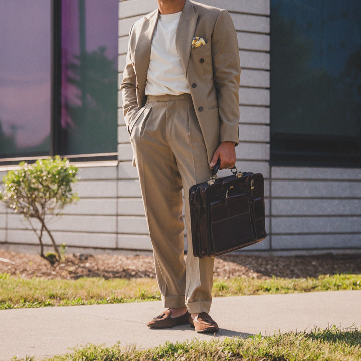 Model in JB Ander Valedictorian tassel loafers in a beige suit holding briefcase