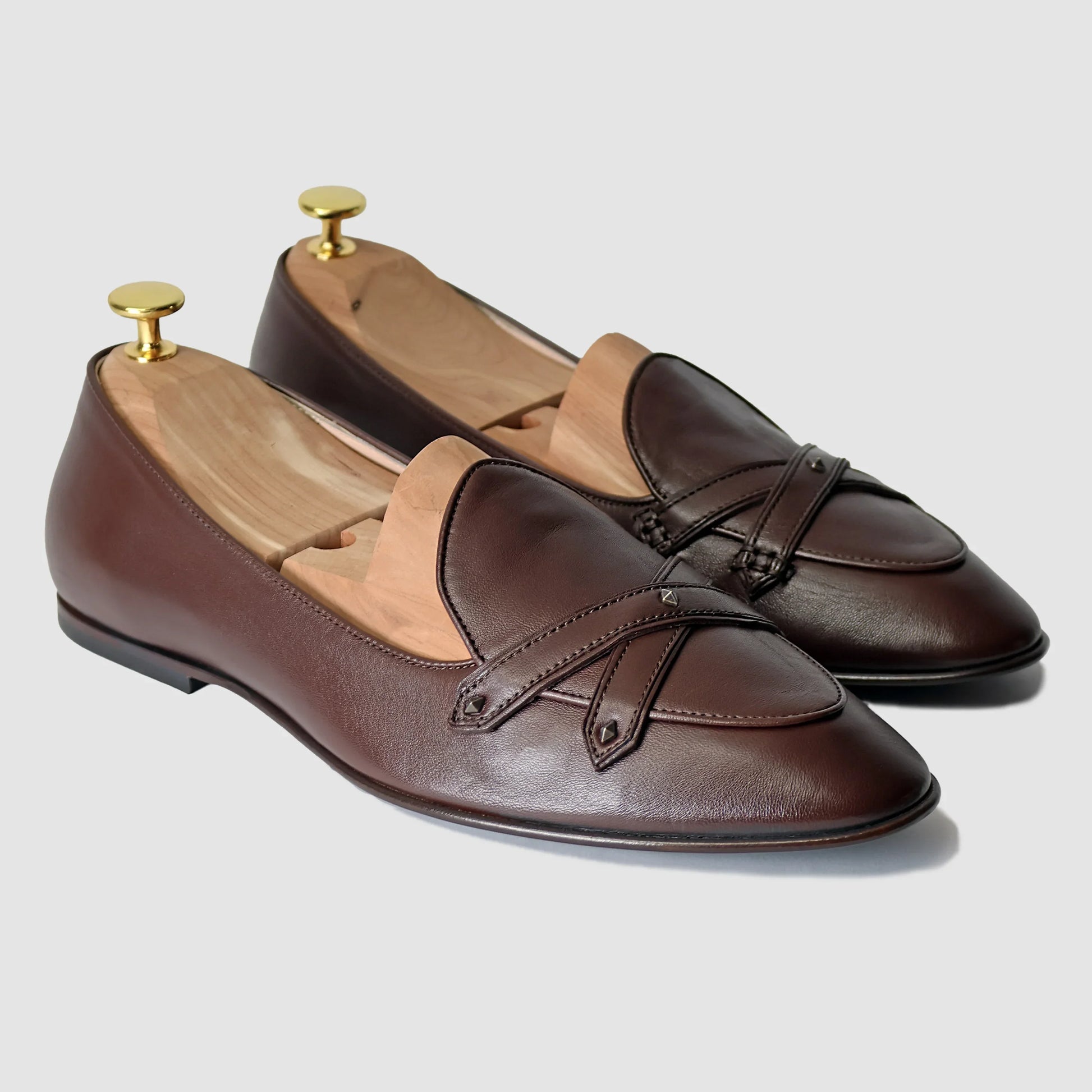 Chestnut brown Italian leather Lincoln saddle loafers by JB Ander, front three-quarter angle showing double cross-strap detail, antiqued gold metal accents, and leather outsole edge.