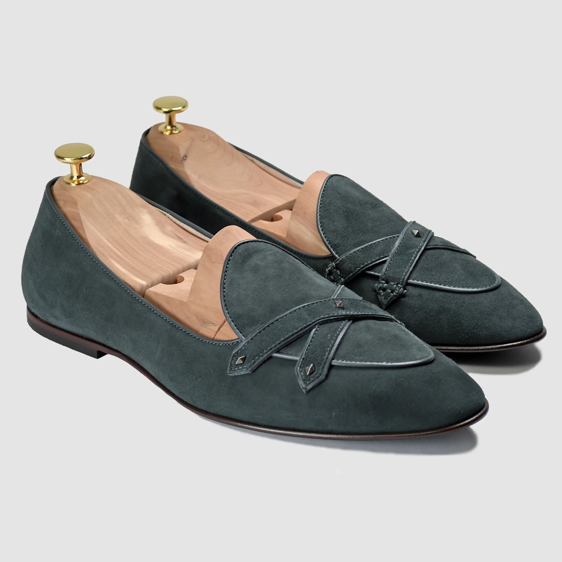Emerald-green suede Lincoln saddle loafers by JB Ander, front three-quarter angle showing double cross-strap detail, wooden cedar shoe trees, and Italian leather outsole edge.