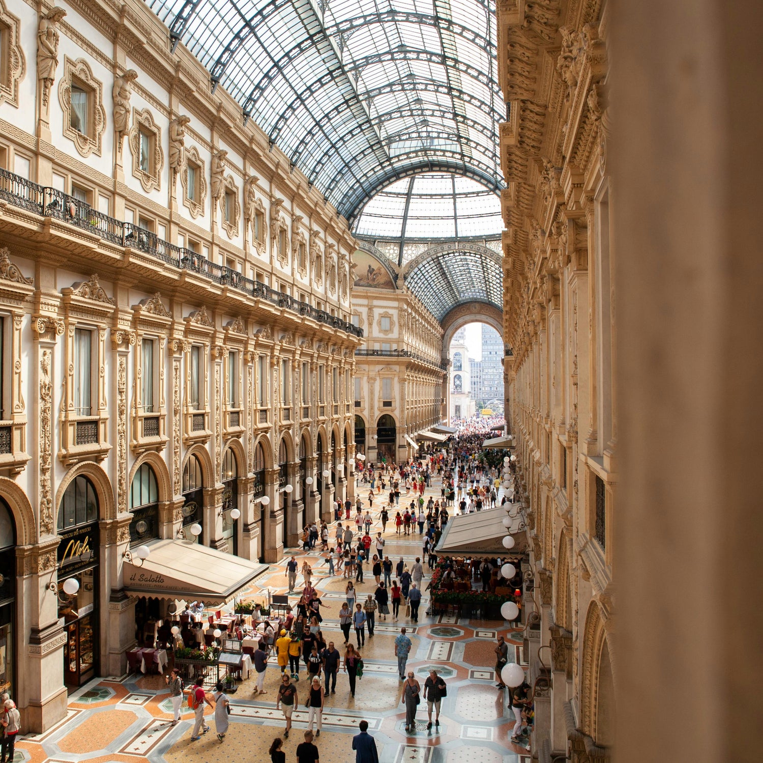 Milan Italy's grand architectural interior of shopping mall with ornate decorations and glass ceiling.