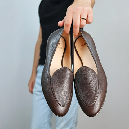 Model holding JB Ander's Venetian loafers in espresso brown pebbled leather, luxurious calfskin insole, and handcrafted in Italy .